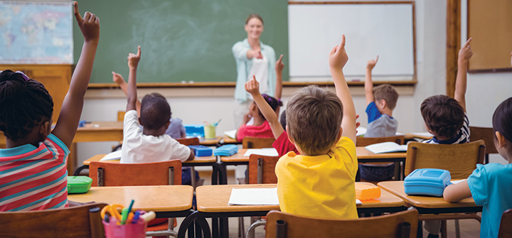 Kids raising their hands in a classroom.